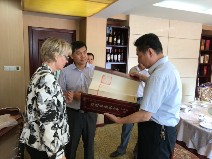 JIN Wei, Amtsleiter des Amts für Land und Ressourcen Qingzhou, überreicht Frau Klopfer ein Gastgeschenk. 